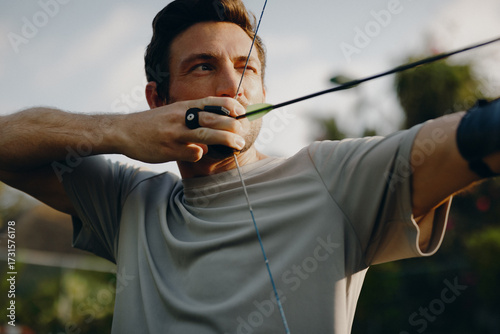 Skillful man practicing archery outdoors