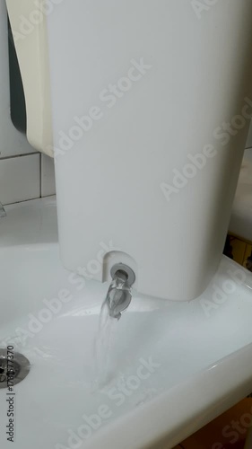 Hand opens special hole in bucket and drains water into sink, cleaning concept household chores