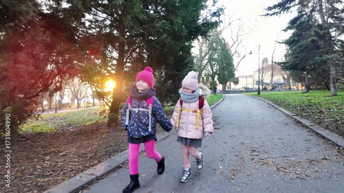Two Happy Girls Walking Hand in Hand in Winter Park. Childhood Friendship, Outdoor Fun, Warm Clothes, Family Lifestyle and Seasonal Concept