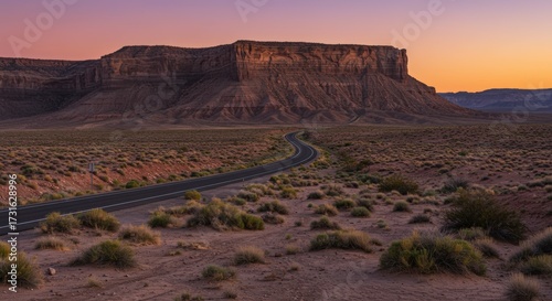 Scenic road through desert landscape under twilight sky with elevated rock formation silhouette