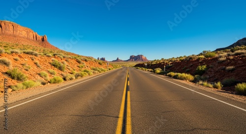 Open highway leading towards distant mountains under a clear blue sky capturing vast landscapes