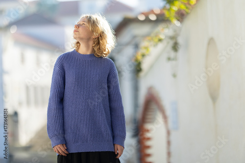 Young person looking up towards the sky in street