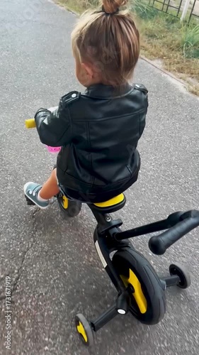Little girl riding a bicycle in the park on a sunny summer day