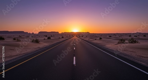 Road stretching towards the sunset with a vast desert landscape under a colorful sky at dusk