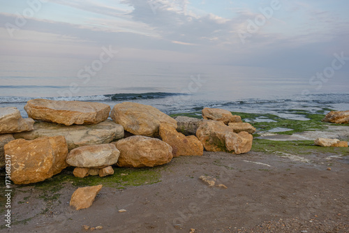 Large stones on the seashore. Evening landscape with a view of the stones by the sea. Sunset at the sea. Walking along the seashore.
