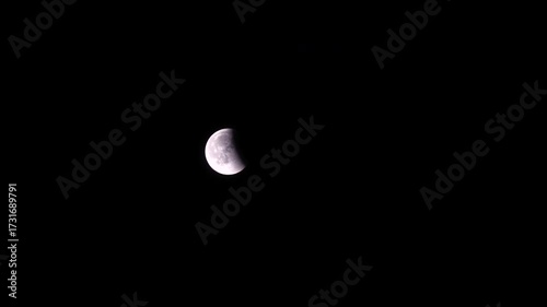 This breathtaking time lapse captures a lunar eclipse, showcasing the moon in a vibrant reddish hue against a backdrop filled with twinkling stars, embodying celestial beauty.