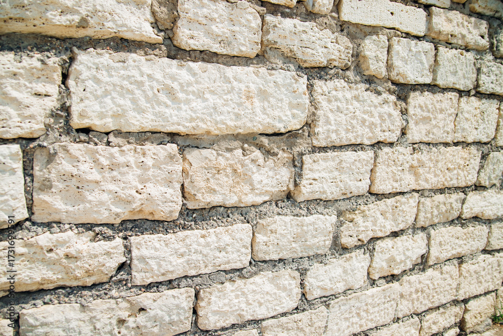 Fototapeta premium Textured wall of rectangular stone blocks in light beige shades and cement between them.