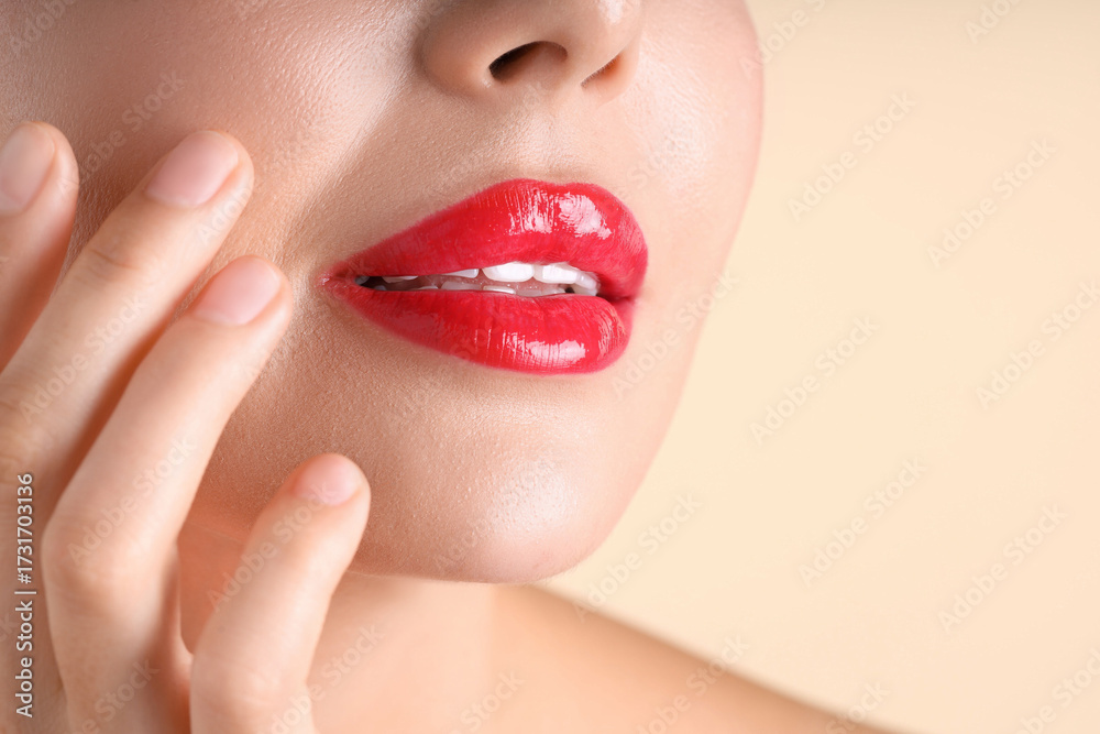 Fototapeta premium Woman with beautiful red lipstick on her lips against beige background, macro view