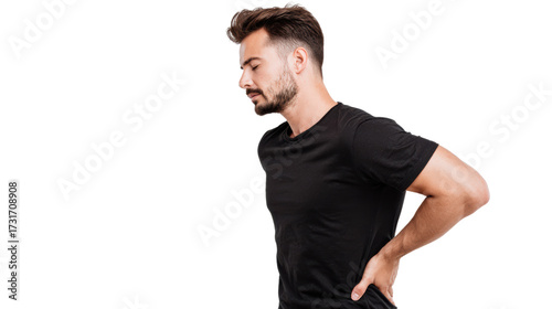 Man experiencing back pain, standing with one hand on his lower back, white isolated background.