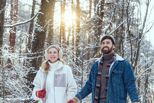 Young couple enjoying a walk in a winter forest and looking happy