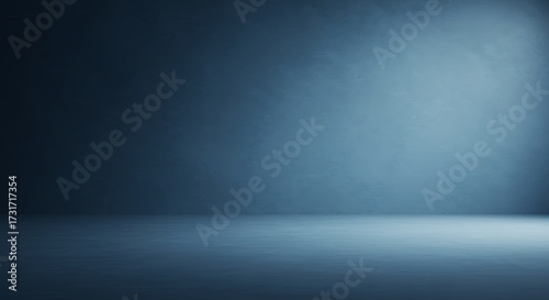 Empty dark blue studio background with subtle spotlight illumination, creating a gradient effect for product display or abstract design.