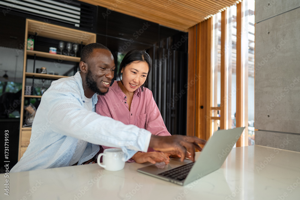 Obraz premium Business team, two happy diverse, multiethnic executives working together using laptop in office.