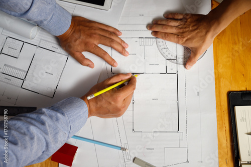 Architects working on house blueprint, drafting construction plan with pencil and tools. Concept of architecture, engineering, teamwork, planning, and real estate design.