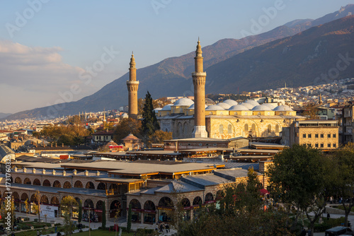 Exterior view of Bursa Grand Mosque (Ulu Camii) with twin minarets and domes against mountain backdrop