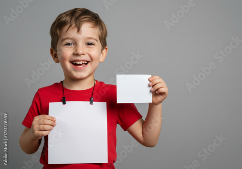 Joyful young boy enthusiastically holds blank white cards, ready to share his ideas or announce something exciting