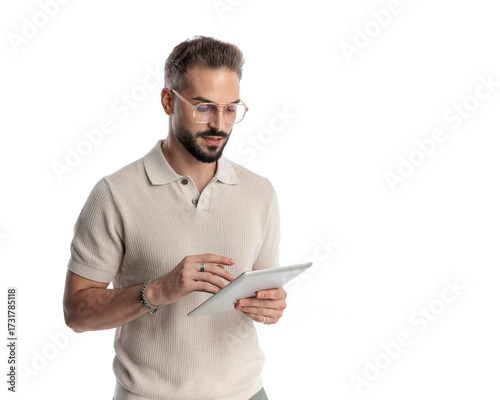 casual young man with glasses looking and touching tablet screen