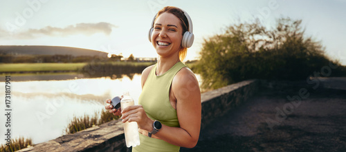 Woman taking a break from exercise by a lake at sunset