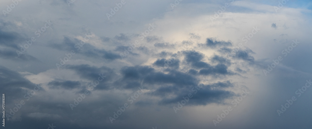 Obraz premium A gray stormy sky partially illuminated by sunlight, creating a dramatic effect of changing weather