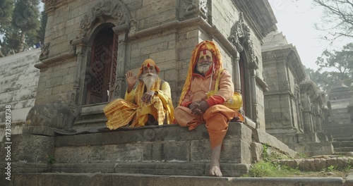 A Sadhu Yogi in yellow attire meditates with sacred hand mudras at Pashupatinath Temple, Kathmandu, Nepal. His devotion to the gods symbolizes Hindu spirituality, culture, and sacred tradition