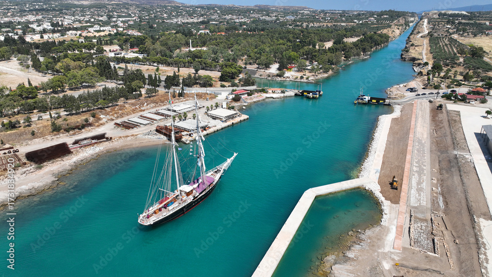 Fototapeta premium Aerial drone photo of classic sailing boat crossing narrow Corinth canal of Isthmus from West submersible bridge and narrow opening of Corinthian gulf to Saronic gulf, Loutraki, Greece
