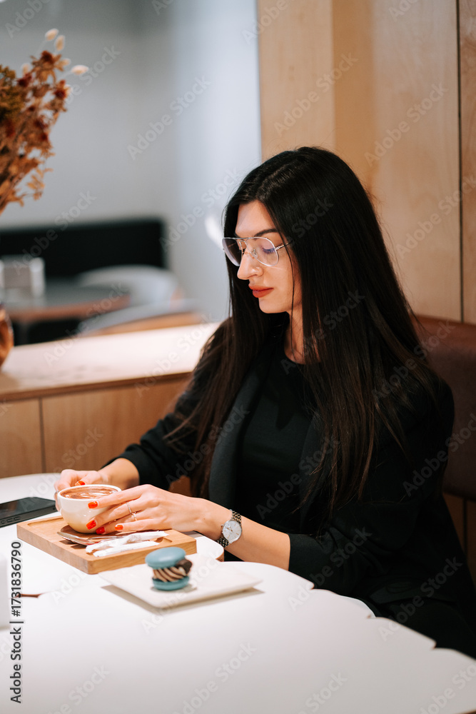 Fototapeta premium Woman enjoying coffee and dessert in a modern cafe setting during the afternoon