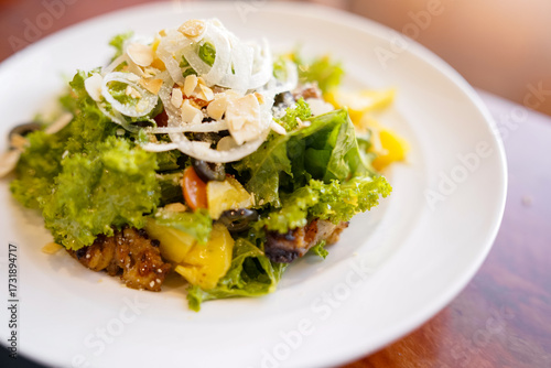 A mixed salad featuring mango, grilled chicken, nuts, and fresh greens served on a white plate. The dish is healthy, colorful, and ready for lunch or a light snack.