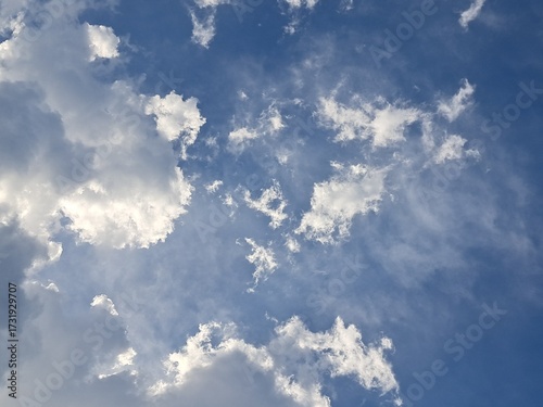 Late afternoon sun illuminating the clouds in the blue sky – White and grey clouds illuminated by the strong rays of the late afternoon sun, amidst a blue sky.