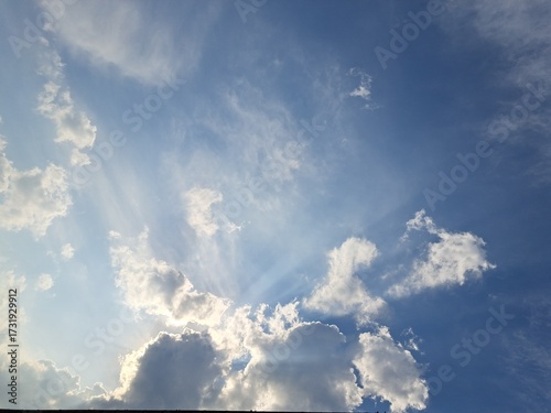 Late afternoon sun illuminating the clouds in the blue sky – White and grey clouds illuminated by the strong rays of the late afternoon sun, amidst a blue sky.