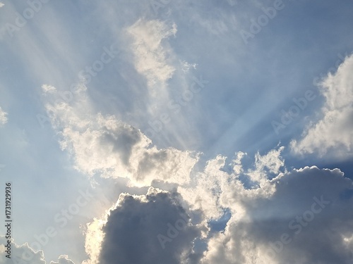 Late afternoon sun illuminating the clouds in the blue sky – White and grey clouds illuminated by the strong rays of the late afternoon sun, amidst a blue sky.