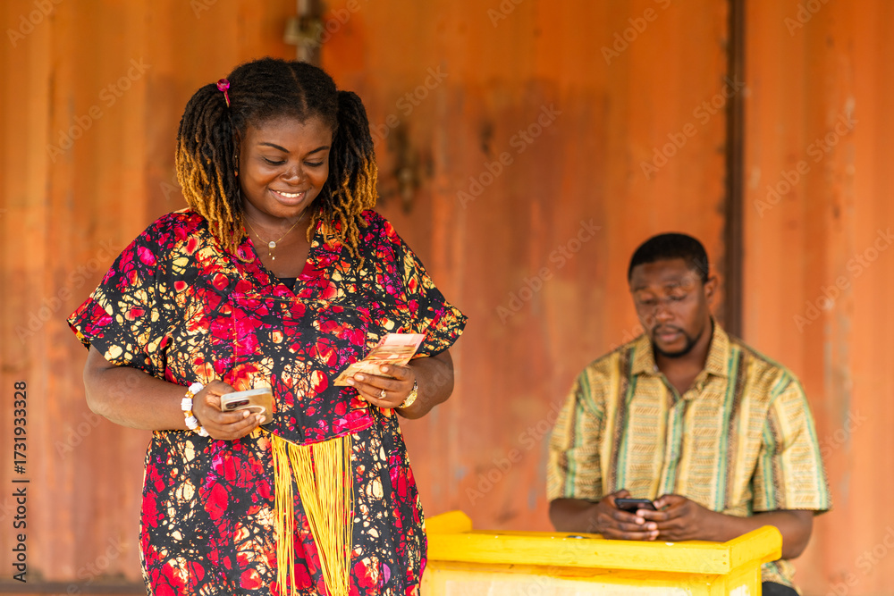 Fototapeta premium Mobile money (MoMo), Happy customer holding cash after withdrawing transaction from an agent.