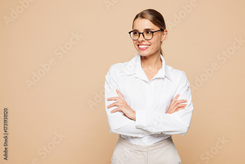 Obraz na plátně Young successful employee business woman corporate lawyer wear classic formal white shirt work in office hold hands crossed folded look aside isolated on plain beige color background studio portrait