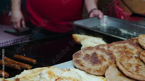 Traditional serbian sausages sremska kobasica and bread lepinja being cooked on street rostilj brazier. Serbian national street food