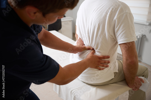 Chiropractor performing manual back adjustment on patient in medical clinic. Physiotherapy, spinal alignment, and rehabilitation treatment for lower back pain relief.