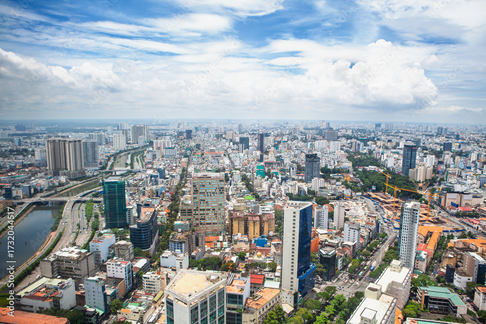 Fototapeta premium Aerial cityscape of Ho Chi Minh City ( Saigon ), Vietnam, showcasing modern skyscrapers, dense urban layout, and river. Biggest Vietnamese metropolis at south part of county on a bright sunny day.