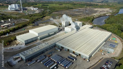 Drone aerial footage of Yorkshire industrial manufacturing site showing factory warehouse, smoke stack plume and River Aire landscape environment