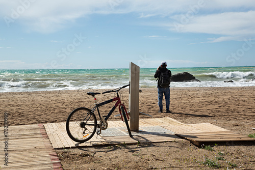 Paisaje de playa con hombre y bicicleta.