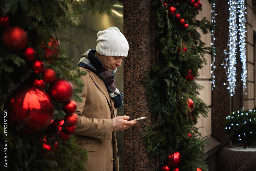 Φωτογραφία Adult man with mobile phone in hand leaves luxury store with festive Christmas decorations