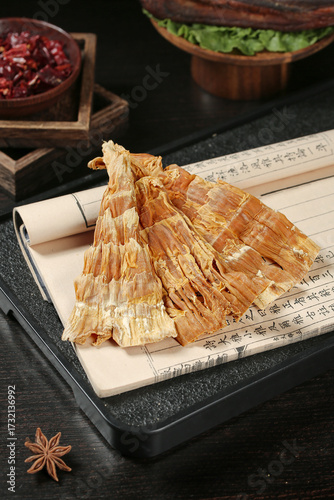 Dried bamboo shoots on traditional paper with Asian spices and wooden bowls in rustic kitchen setting