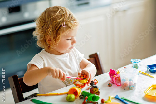 Photography Adorable cute little toddler girl with colorful clay at home