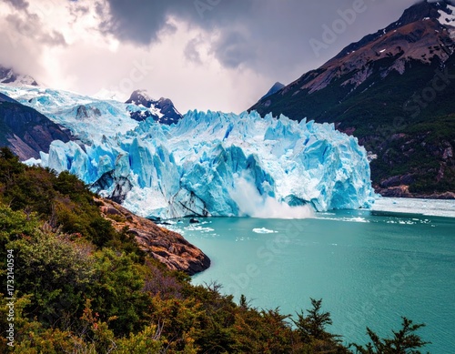 Glacial ice calving into turquoise lake, dramatic mountains