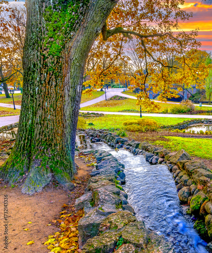 Small decorative water cascade in public city park at autumn season
