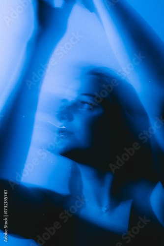 Dreamy moody cinematic portrait of a brunette woman with blue-aqua glow and long exposure