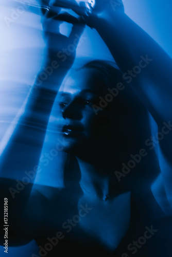 Dreamy moody cinematic portrait of a brunette woman with blue-aqua glow and long exposure