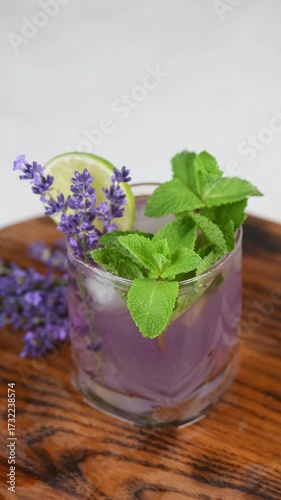Lavender Mojito cocktail with lavender syrup, lime juice, tequila with tonic, lavender sprigs and mint. Vertical video. Close-up. Circular movement