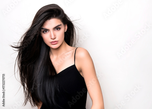 Beautiful young woman with long black hair posing in black dress 