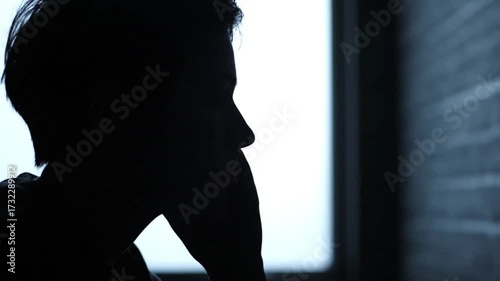 Silhouette of a man expressing sadness and grief in the dark with hand on his forehead and face video 4k