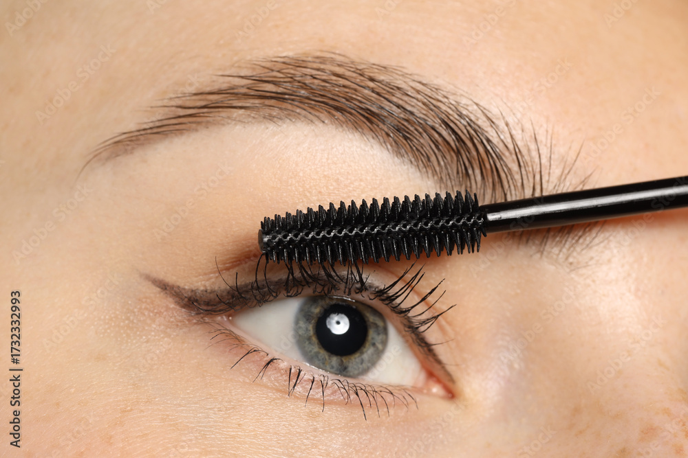 Naklejka premium Woman applying mascara onto her eyelashes, closeup