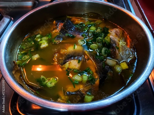 Silver catfish in yellow soup cooked in a stainless steel bowl.