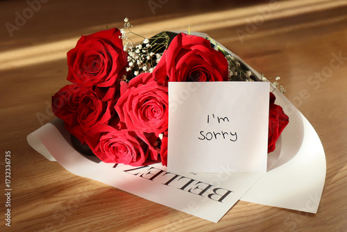 A bouquet of red roses and a note with the text 