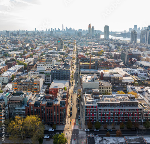 Aerial view of urban canyons carved by streets lined with buildings, a parade of New York Marathon runners, stretch towards the distant Manhattan skyline, Brooklyn, New York, United States.